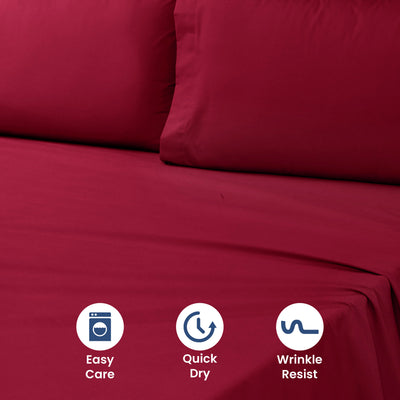 Deep red sheet set with two matching pillowcases on a flat surface.