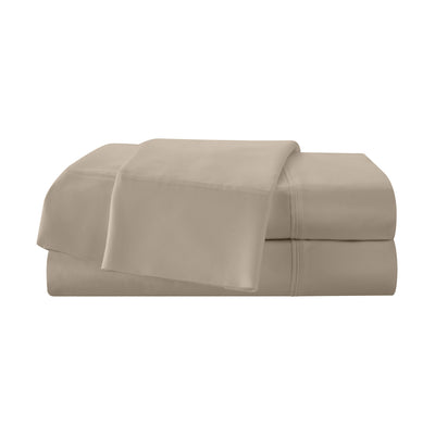 Beige cotton sheet set stacked neatly with a top sheet partially draped over the fitted sheet.