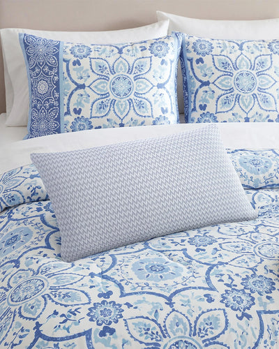 Blue decorative pillow on a bed.