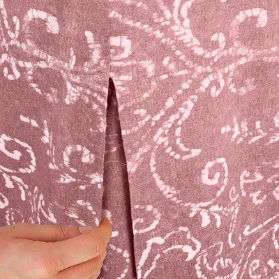 Close-up of a patterned table cover with a hand adjusting a slit in the fabric.