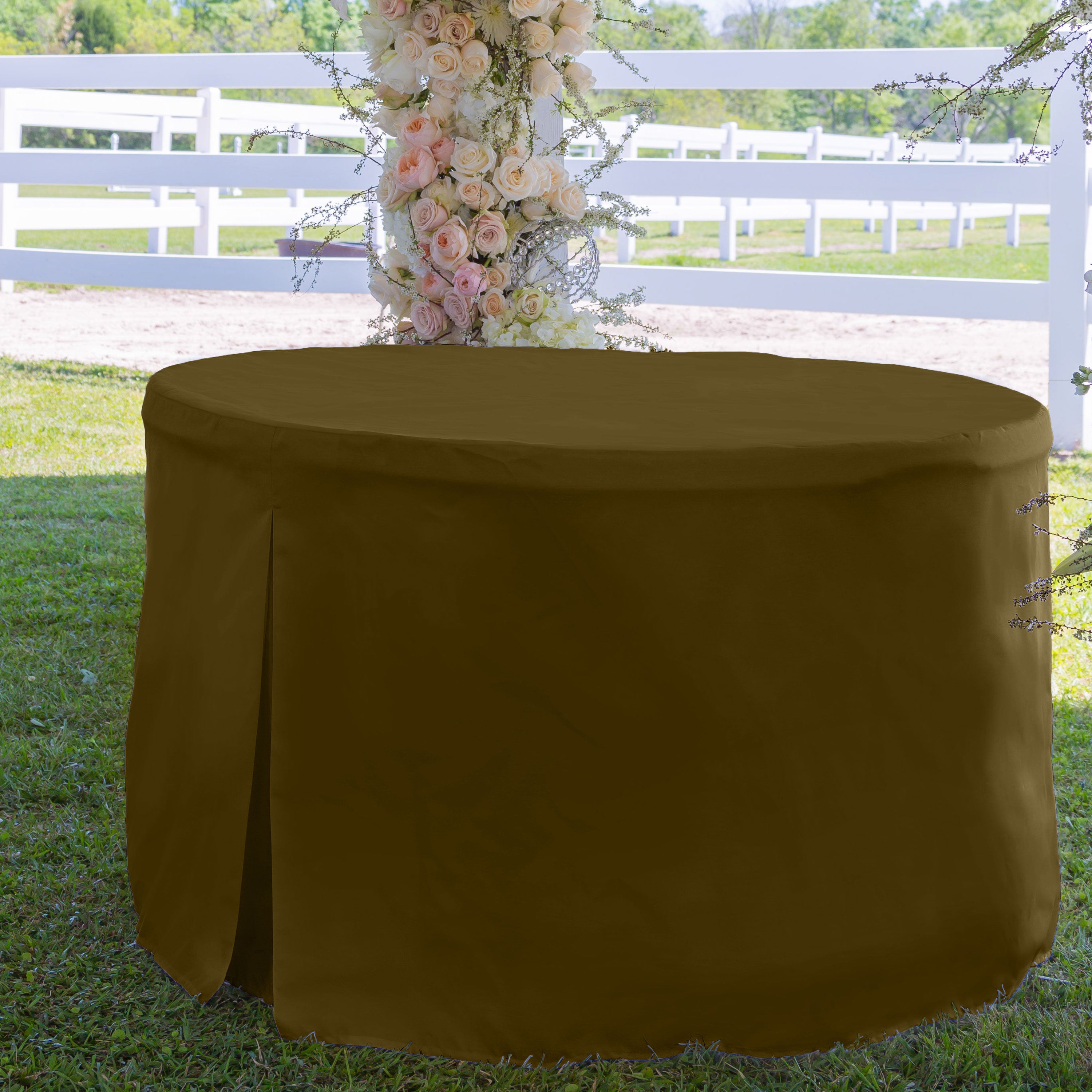 Round table cover in a solid brown color, designed for a 60-inch table, set on grass with floral decor in the background.