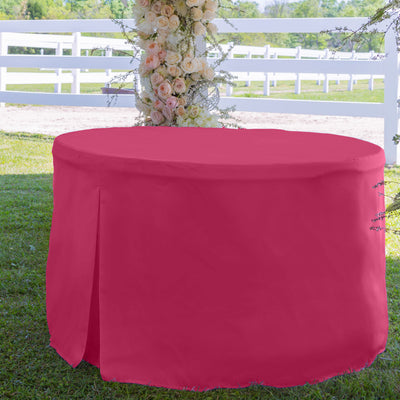 Round table cover in bright pink, designed for a 60-inch table, set on grass with a floral backdrop.