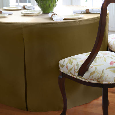 Round table covered with a solid brown tablecloth, surrounded by chairs with floral-patterned cushions.