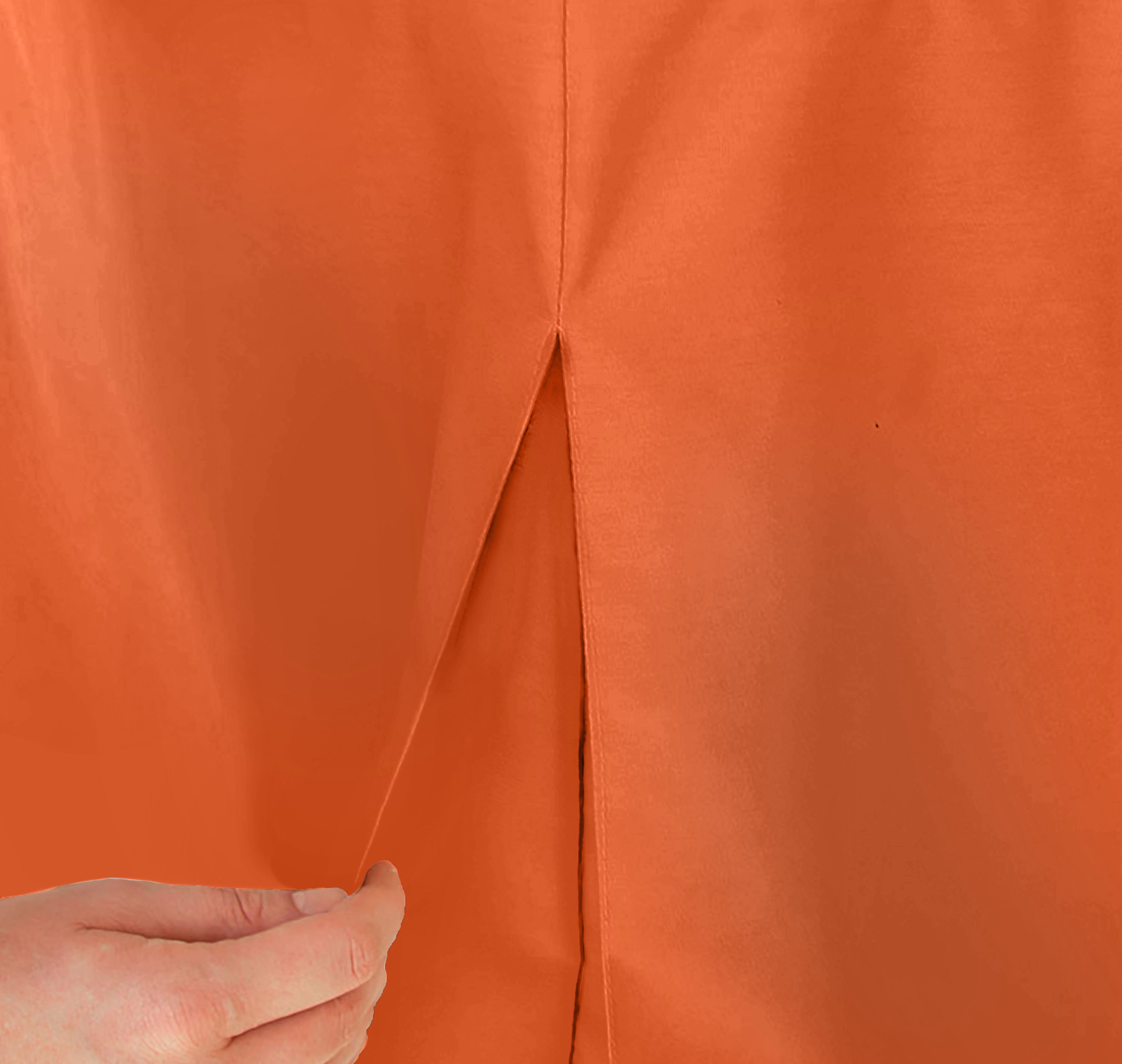Close-up of an orange table cover with a slit, being held by a hand.