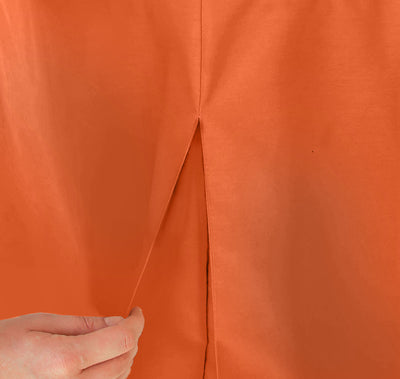 Close-up of an orange table cover with a slit, being held by a hand.