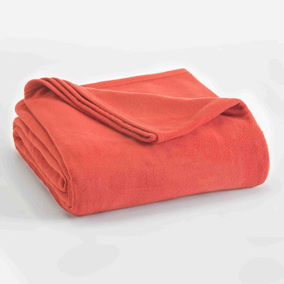 Coral micro fleece blanket folded with a smooth texture and a slightly rolled edge.