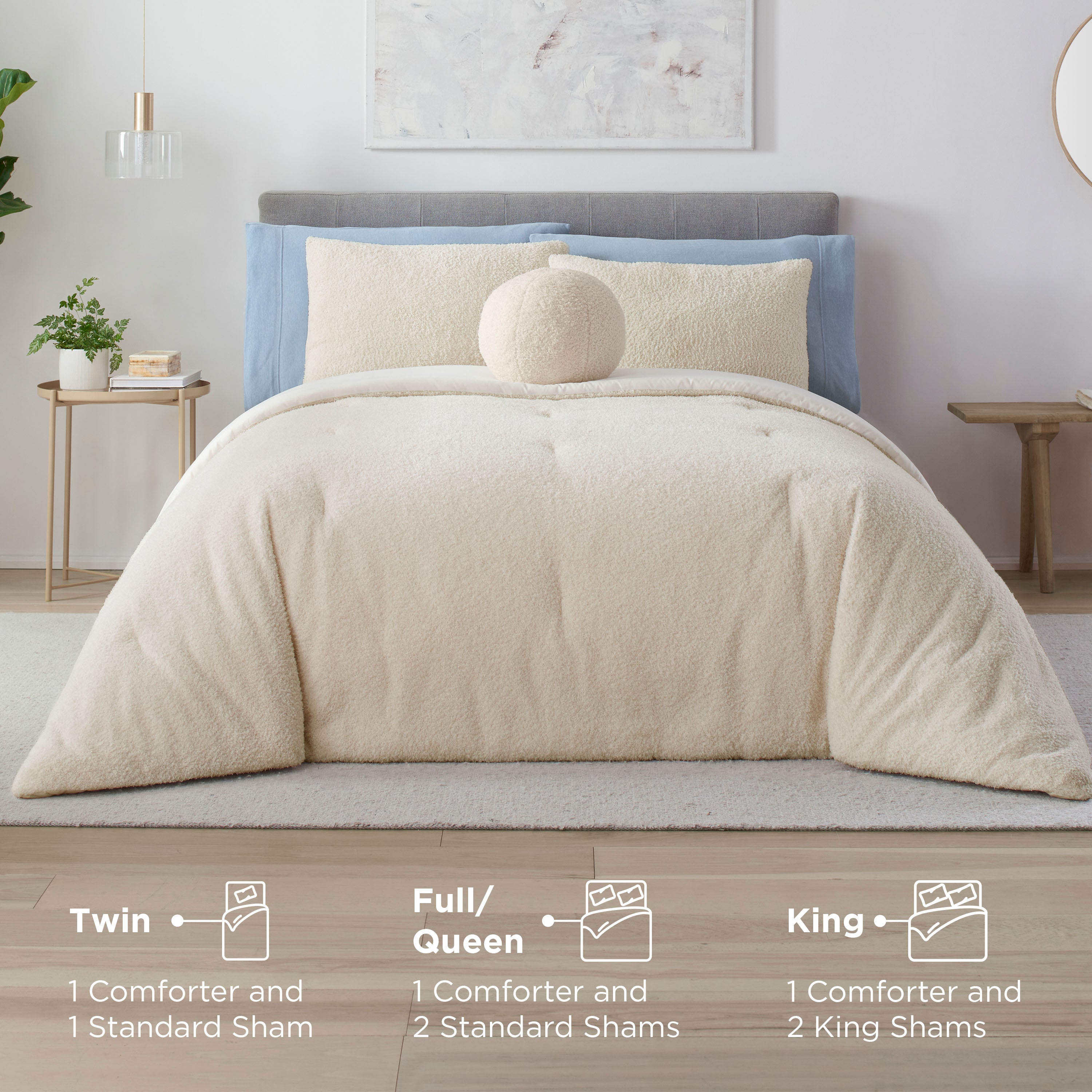 Cream-colored comforter set with matching shams and a round decorative pillow on a bed with a gray headboard.
