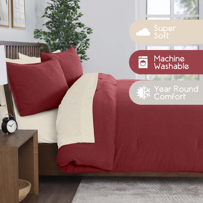 Burgundy comforter set with cream accents and two matching pillows on a bed, beside a nightstand and plant.