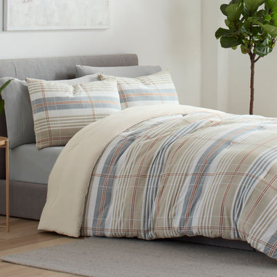 Comforter set featuring a taupe and plaid design with matching pillow shams on a bed with a gray headboard.