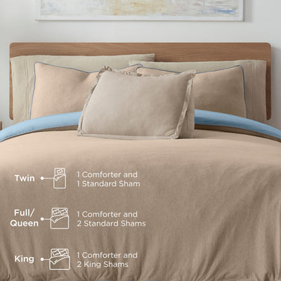 Comforter set displayed on a bed with various pillows and shams in neutral tones and a blue accent.