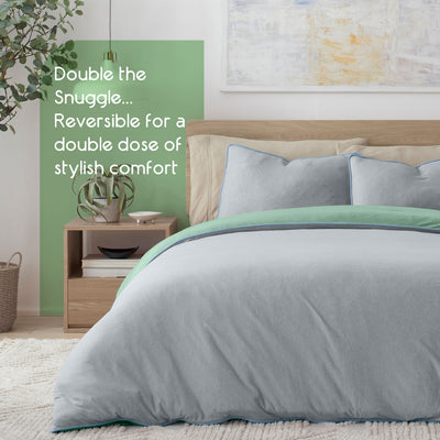 Reversible comforter set in gray with green accents, paired with matching pillows on a bed in a modern bedroom setting.