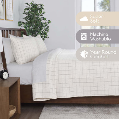 Coverlet set featuring a grid pattern, two pillows, and a light color scheme on a bed with a wooden frame.