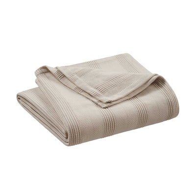 Beige cotton blanket folded with a textured pattern and a hemmed edge.