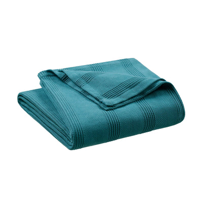 Teal cotton blanket folded with a textured pattern and a corner turned down.