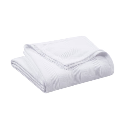 White cotton blanket folded with a textured pattern and a corner turned down.
