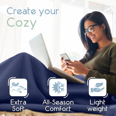 A woman sits comfortably with a laptop and phone, wrapped in a blue micro fleece blanket.