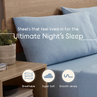 Light blue sheet set on a bed with two matching pillows, accompanied by a small potted plant on a wooden nightstand.