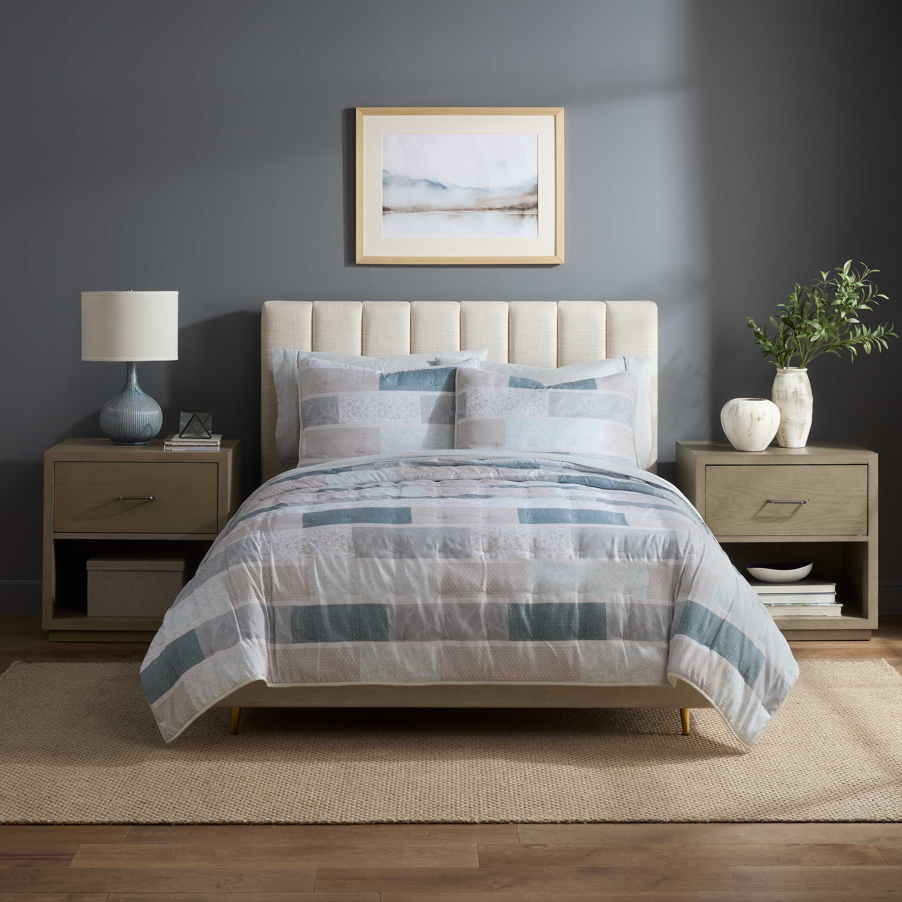 Quilt set featuring a patchwork design in soft colors on a bed with a tufted headboard and matching pillows.
