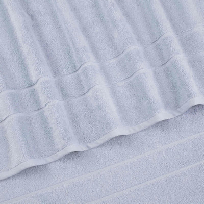 A close-up of a blue terry cloth bath towel with a textured striped pattern and folded edges.