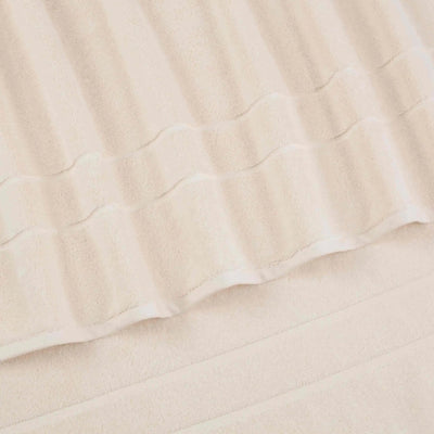 A close-up of a ivory terry cloth bath towel with a textured striped pattern and folded edges.