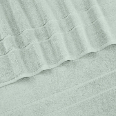 A close-up of a sage terry cloth hand towel with a textured striped pattern and folded edges.