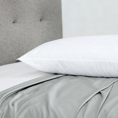 White pillow on a bed with gray bedding and headboard