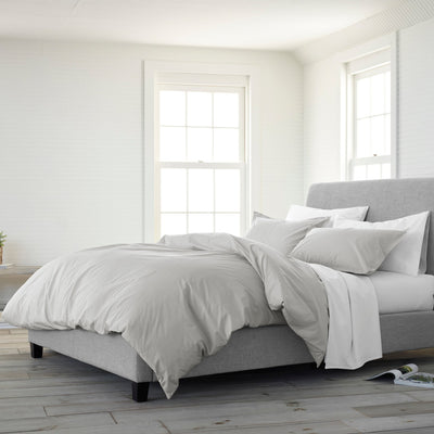 Gray upholstered bed with white bedding in a bright bedroom