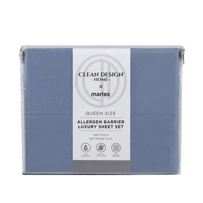 A packaged bedding set in a dusty blue color, wrapped in clear plastic with a white paper label that reads 'Clean Design Home x matrex Queen Size Allergen Barrier Luxury Sheet Set'.