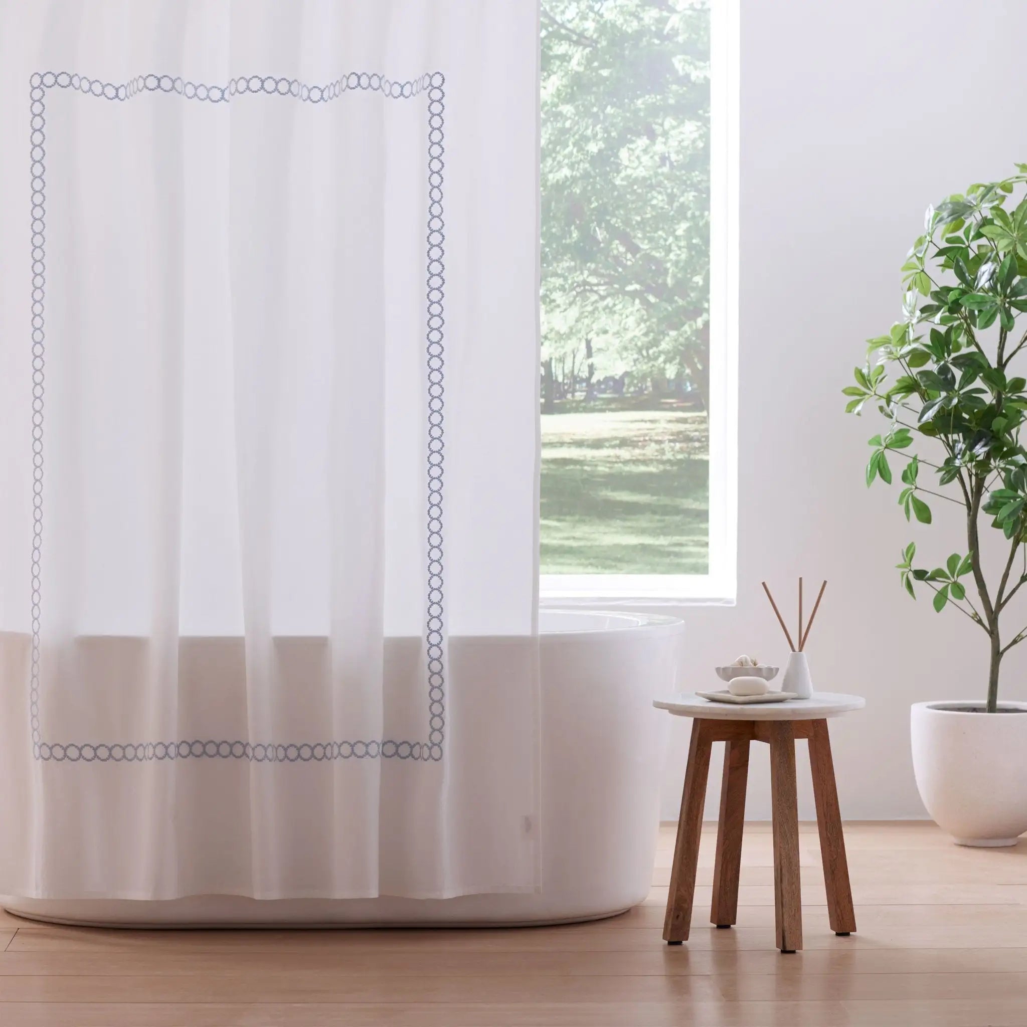 White shower curtain with decorative blue border in a bathroom setting