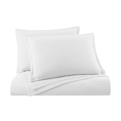 White bedding set with two pillows and a coverlet on a white background