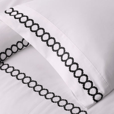 White pillowcases with black chain-patterned trim on a white background