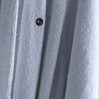 Close-up of a light blue textured fabric with vertical folds and a small black circular logo near the center.