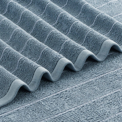 Textured blue towel with slub stripe pattern, folded in waves.