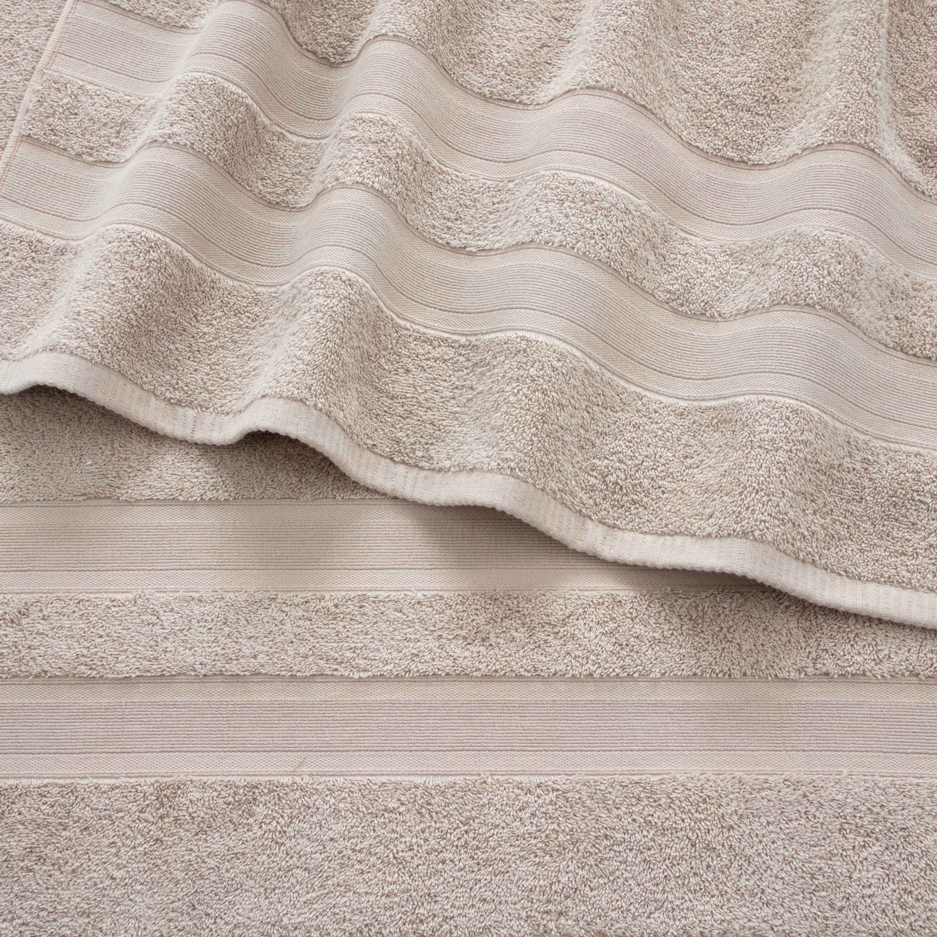 Solid beige towels with textured stripes, arranged in a layered fashion.