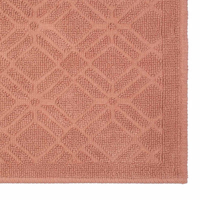 Textured bath rug in a soft pink hue featuring a geometric pattern.