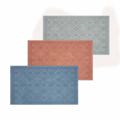 Three rectangular bath rugs in blue, coral, and light green with a geometric pattern.