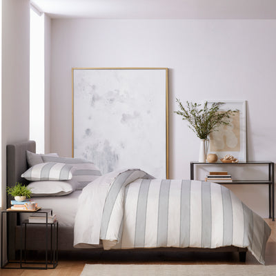 Duvet set featuring gray and white striped bedding on a bed with decorative pillows and a minimalist room decor.