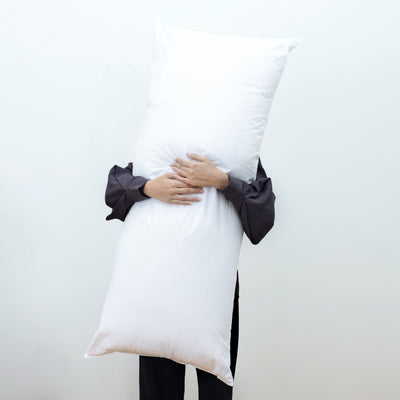 A person holds a large, white gusset pillow against a plain background.