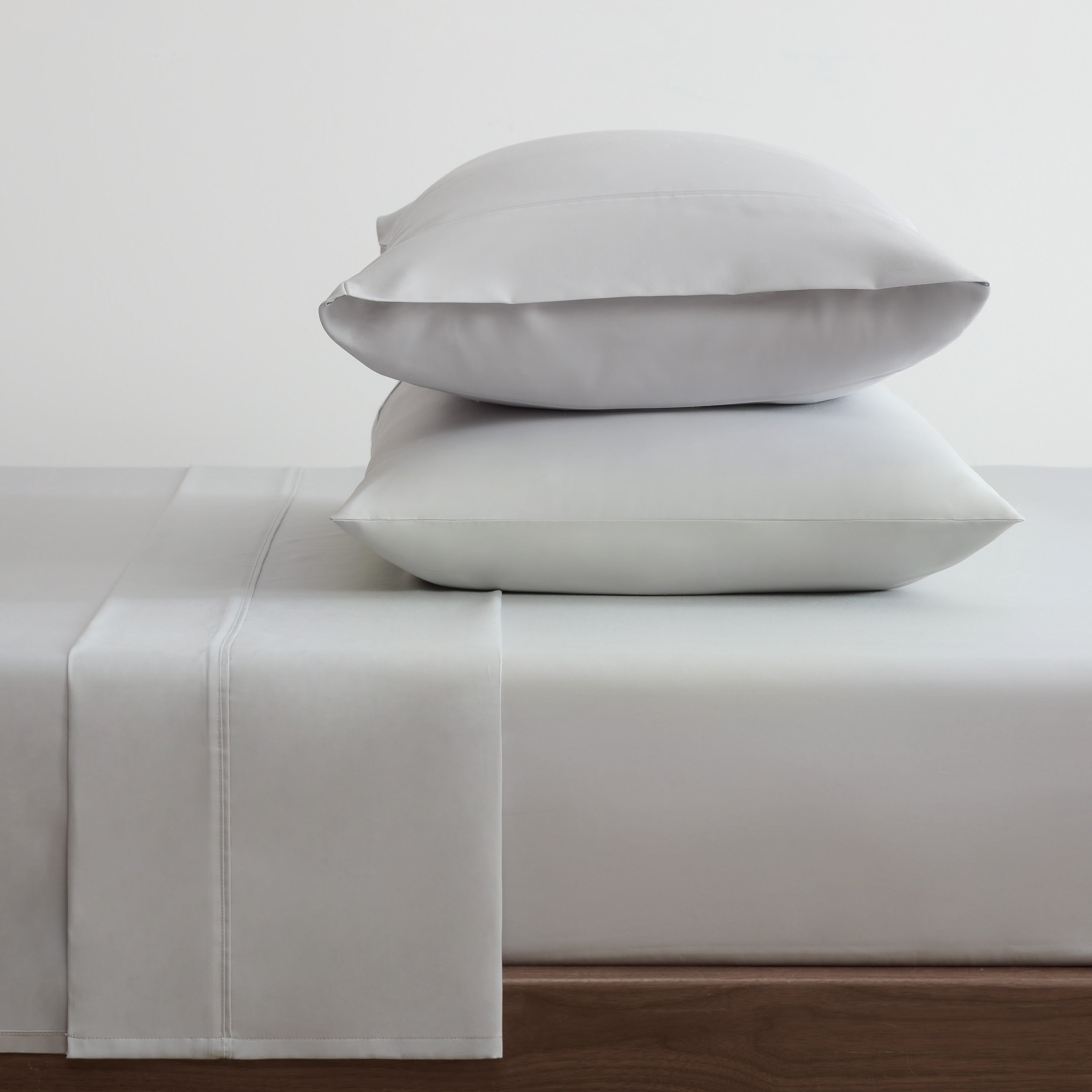 Gray cotton and Tencel sheet set with two stacked pillows on a bed.