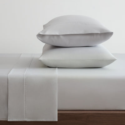 Gray cotton and Tencel sheet set with two stacked pillows on a bed.