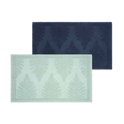 Two bath rugs featuring fern patterns, one in navy blue and the other in light green.