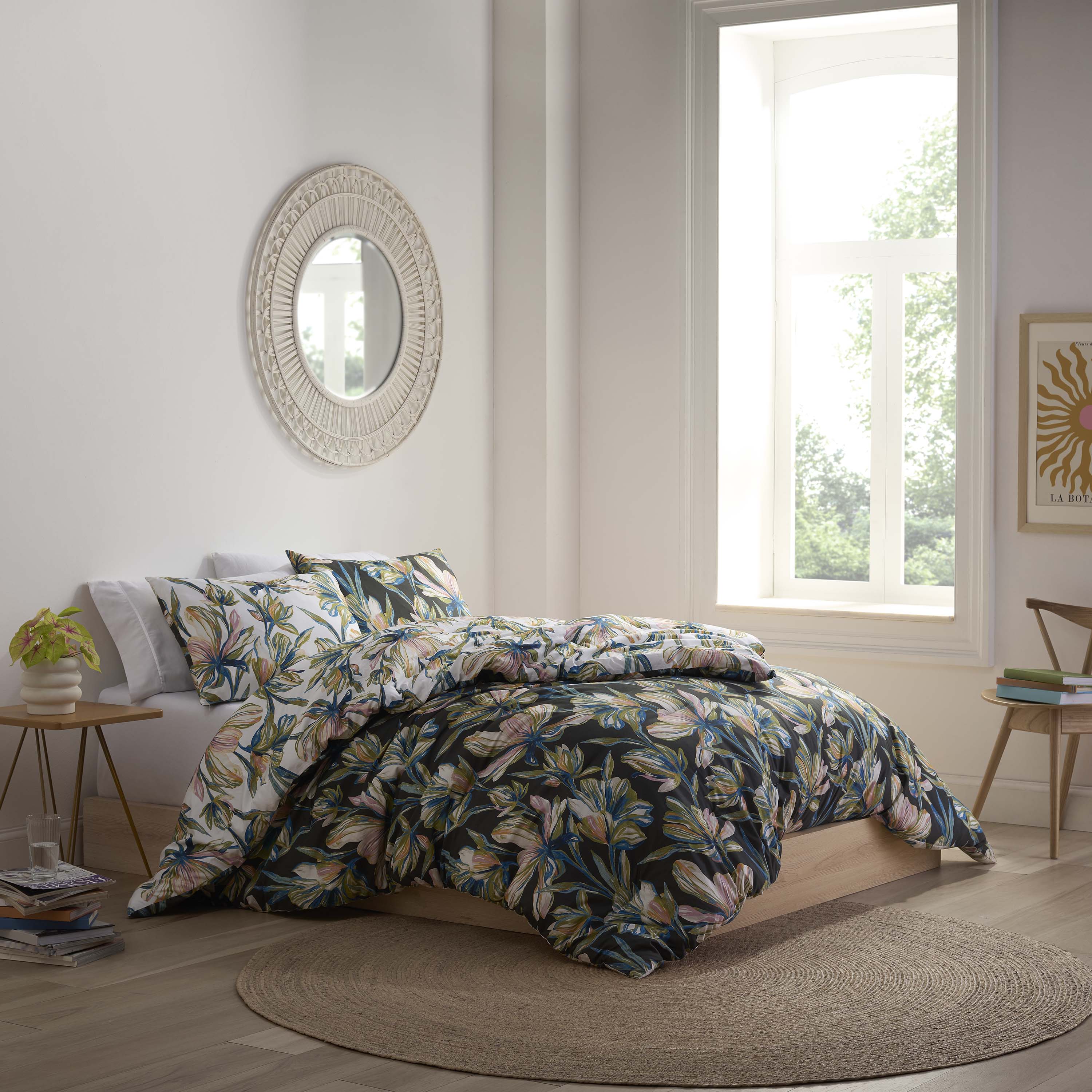 Comforter set featuring a floral design in shades of green, pink, and blue on a dark background, with matching pillows.
