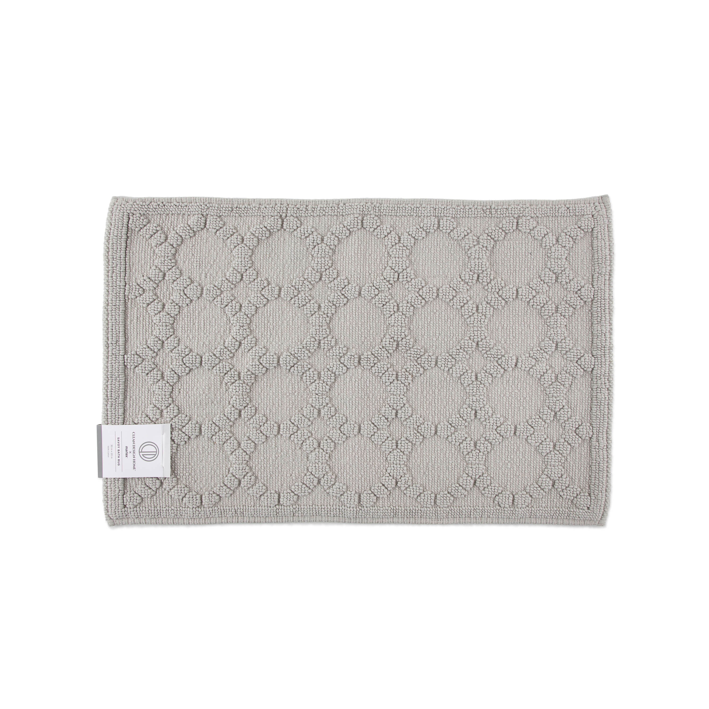Gray bath rug with a textured circular pattern and a label on one corner.