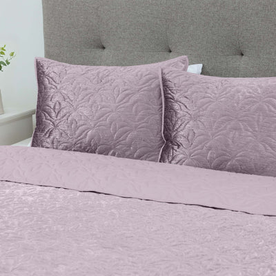Purple quilt set on a bed with a gray upholstered headboard.