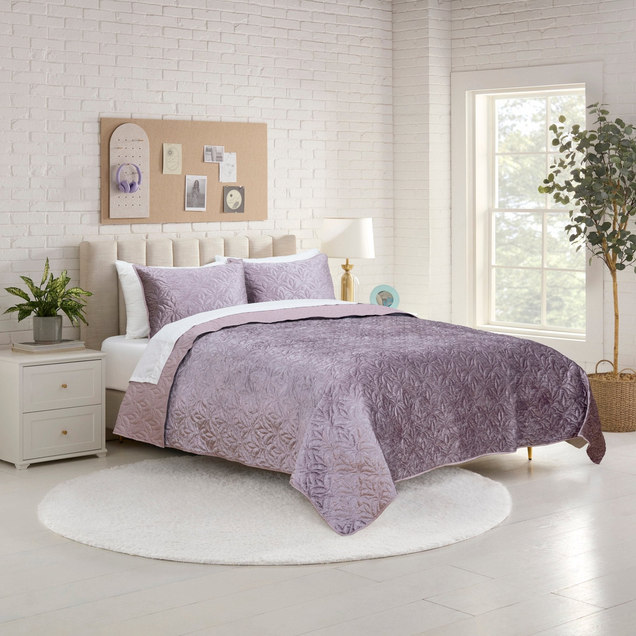 Bedroom with a bed covered in a purple quilt set.