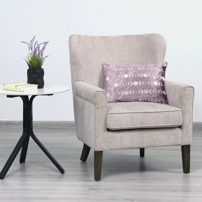 A light beige upholstered armchair with a patterned purple throw pillow.