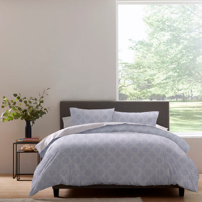 Duvet set featuring a light blue pattern with circular designs, arranged on a bed with matching pillows.