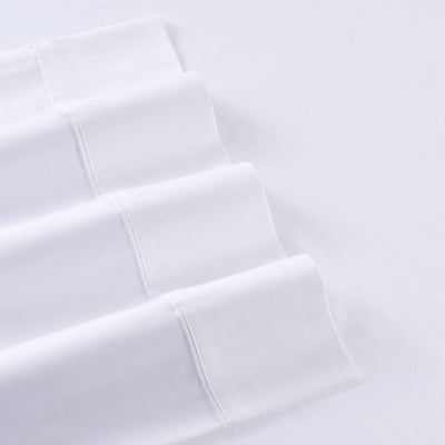 White cotton and Tencel sheet set with smooth, folded edges displayed on a flat surface.
