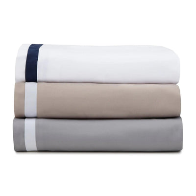 Stack of three folded bed sheets in white, beige, and gray on a white background