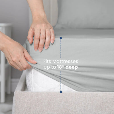 Person adjusting a fitted sheet on a mattress with text indicating it fits mattresses up to 18 inches deep.